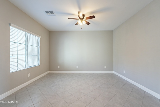 spare room with a ceiling fan, visible vents, and baseboards