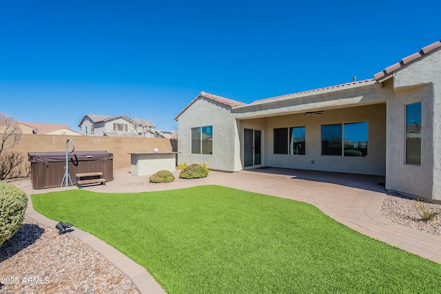 rear view of house featuring a patio area, stucco siding, a fenced backyard, and a hot tub