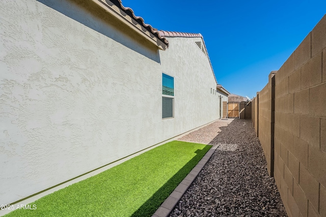 view of property exterior with a tile roof, a gate, fence, and stucco siding