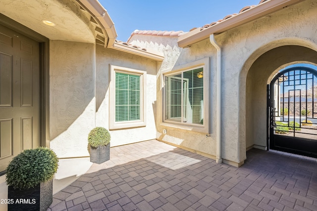 view of exterior entry featuring a patio area, a tile roof, and stucco siding