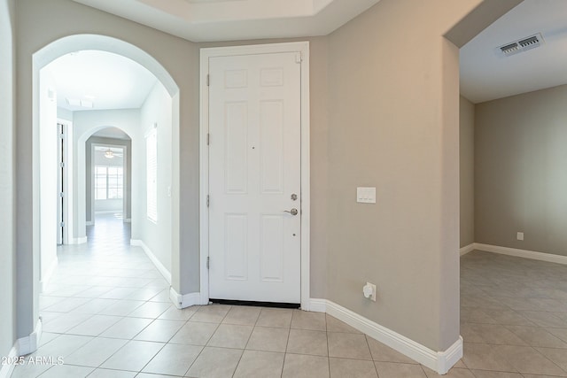 entryway featuring arched walkways, light tile patterned flooring, visible vents, and baseboards