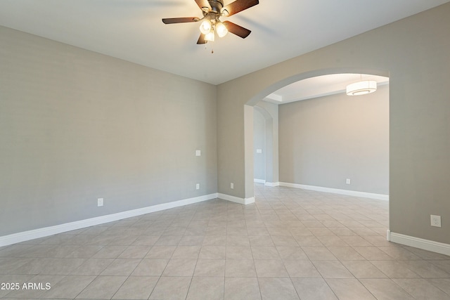 spare room with arched walkways, ceiling fan, and baseboards