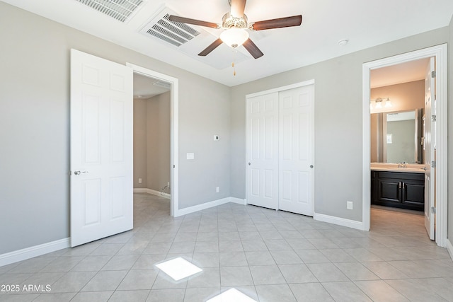 unfurnished bedroom with light tile patterned floors, baseboards, visible vents, a sink, and a closet