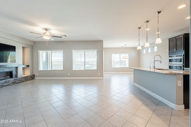 kitchen with light stone counters, open floor plan, a sink, and light tile patterned floors