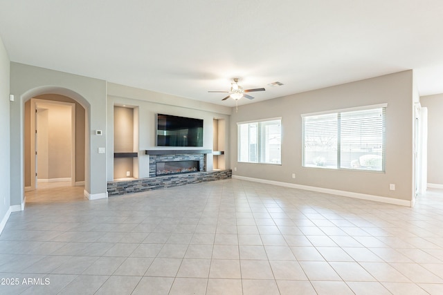 unfurnished living room with visible vents, ceiling fan, a stone fireplace, and light tile patterned flooring