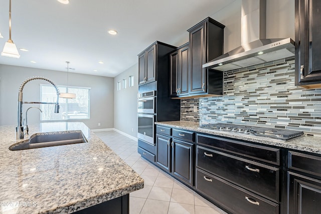 kitchen featuring light stone counters, wall chimney range hood, and decorative light fixtures