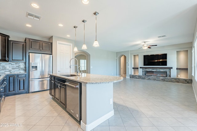 kitchen with stainless steel fridge, a kitchen island with sink, visible vents, and a sink