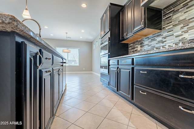 kitchen featuring light stone counters, decorative light fixtures, decorative backsplash, light tile patterned flooring, and wall chimney exhaust hood