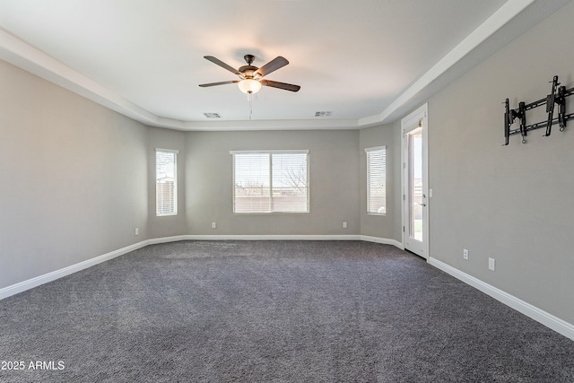 empty room featuring a ceiling fan, dark colored carpet, visible vents, and baseboards