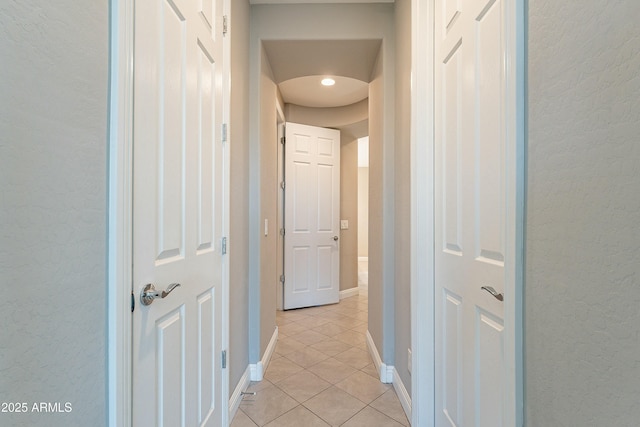 corridor with light tile patterned floors and baseboards