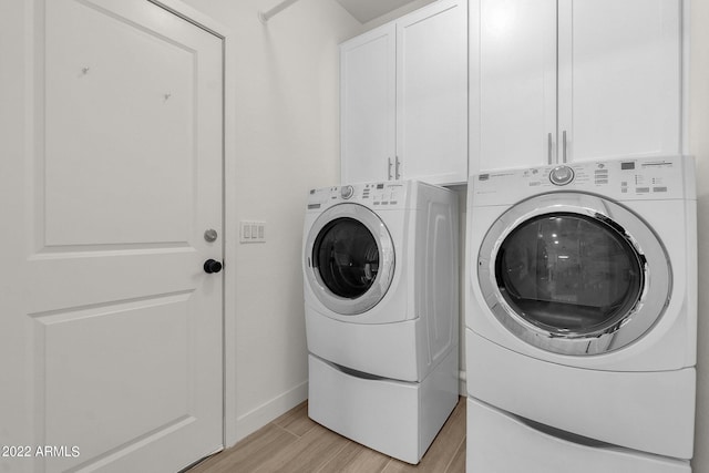 laundry room with washer and clothes dryer, cabinets, and light hardwood / wood-style flooring