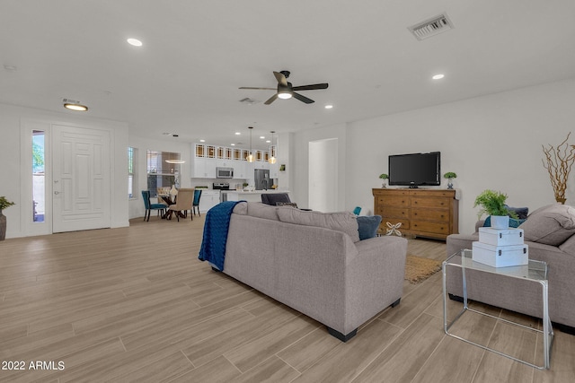 living room with ceiling fan and light wood-type flooring