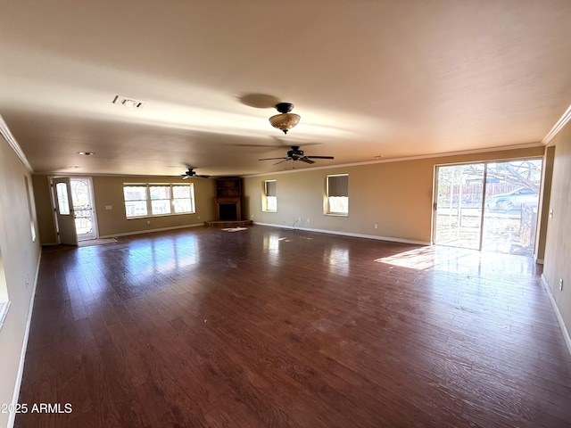 unfurnished living room with visible vents, ornamental molding, dark wood-type flooring, ceiling fan, and baseboards