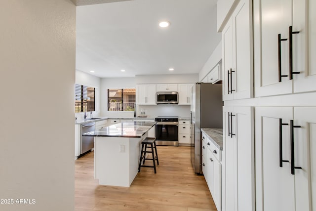 18818 N 95th Ave, Peoria, AZ 85382 - kitchen featuring white cabinets, a kitchen island, appliances with stainless steel finishes, light wood-style floors, and a breakfast bar area