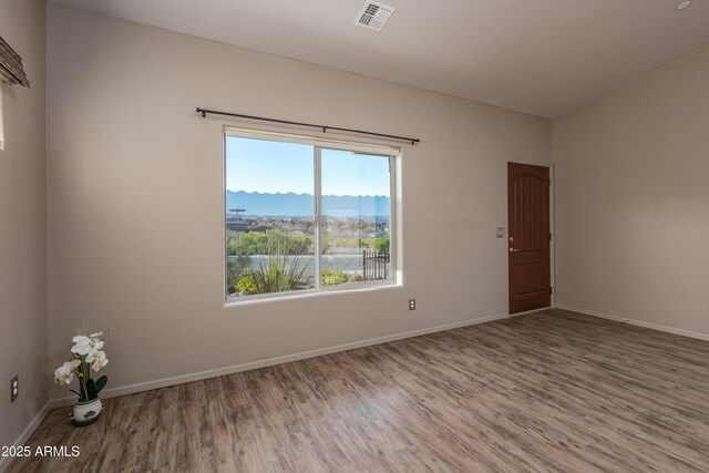 unfurnished room featuring a mountain view, wood finished floors, visible vents, and baseboards