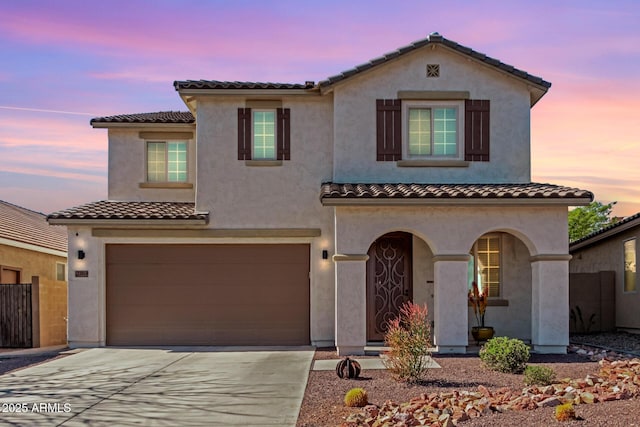 view of front facade featuring stucco siding, driveway, a tile roof, and a garage