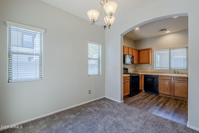 14881 W Ashland Ave, Goodyear, AZ 85395 - kitchen with black appliances, dark colored carpet, a sink, a chandelier, and arched walkways