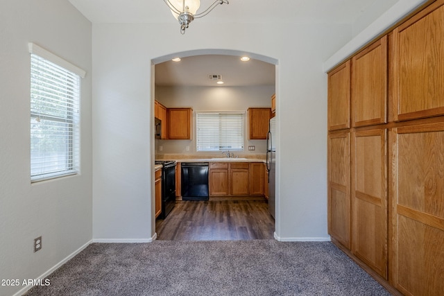 14881 W Ashland Ave, Goodyear, AZ 85395 - kitchen with black appliances, dark colored carpet, arched walkways, a sink, and light countertops