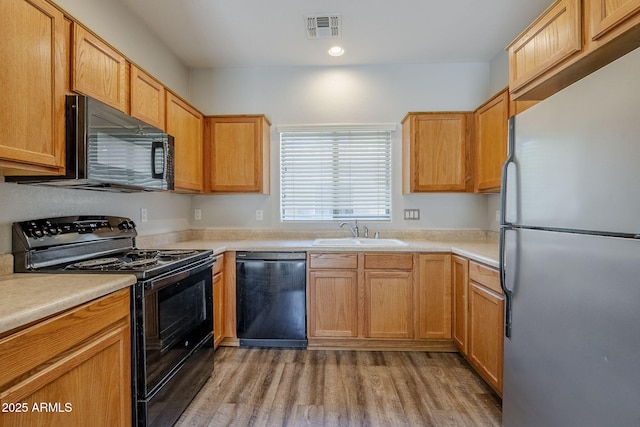 14881 W Ashland Ave, Goodyear, AZ 85395 - kitchen with black appliances, a sink, light wood-style flooring, light countertops, and recessed lighting