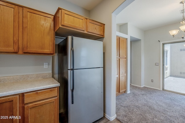 14881 W Ashland Ave, Goodyear, AZ 85395 - kitchen featuring freestanding refrigerator, light carpet, brown cabinets, and a chandelier