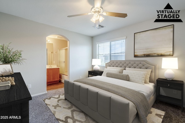14881 W Ashland Ave, Goodyear, AZ 85395 - bedroom featuring arched walkways, light colored carpet, connected bathroom, baseboards, and a ceiling fan