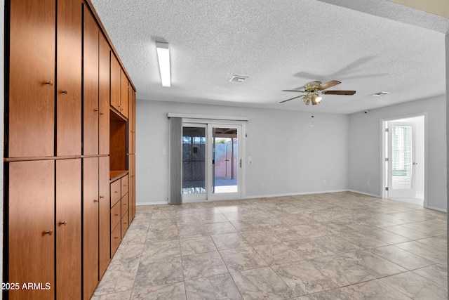 spare room featuring ceiling fan, a textured ceiling, and a healthy amount of sunlight