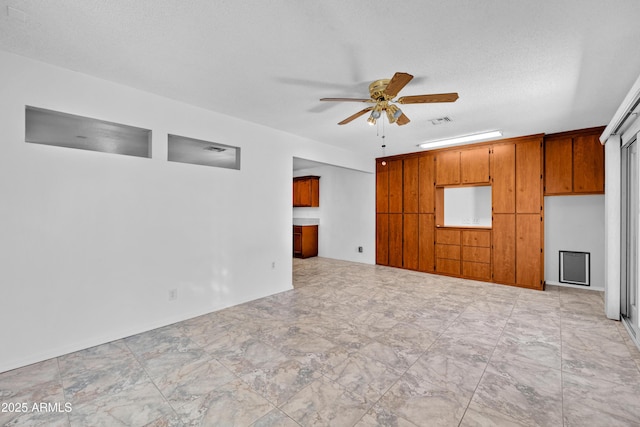 unfurnished living room featuring ceiling fan and a textured ceiling