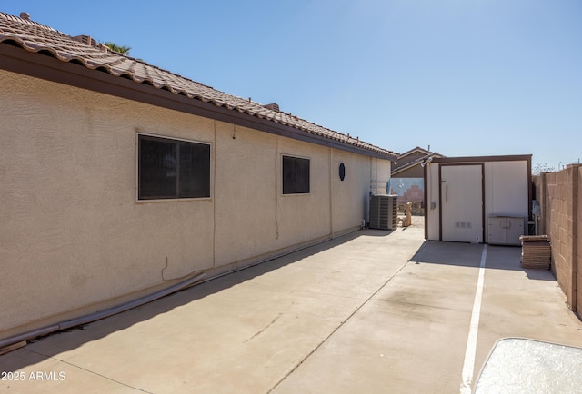 view of property exterior featuring a patio area, central air condition unit, and a storage shed