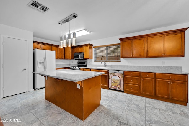 kitchen with stainless steel appliances, sink, light stone countertops, pendant lighting, and a center island