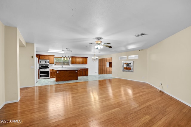 unfurnished living room featuring ceiling fan with notable chandelier, light hardwood / wood-style flooring, and sink