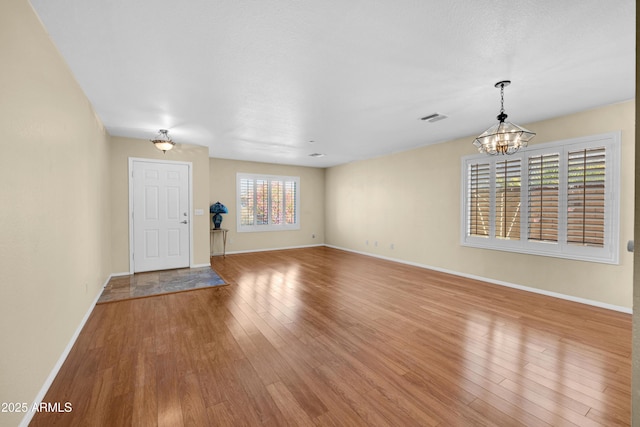 unfurnished living room featuring light wood-type flooring and a notable chandelier