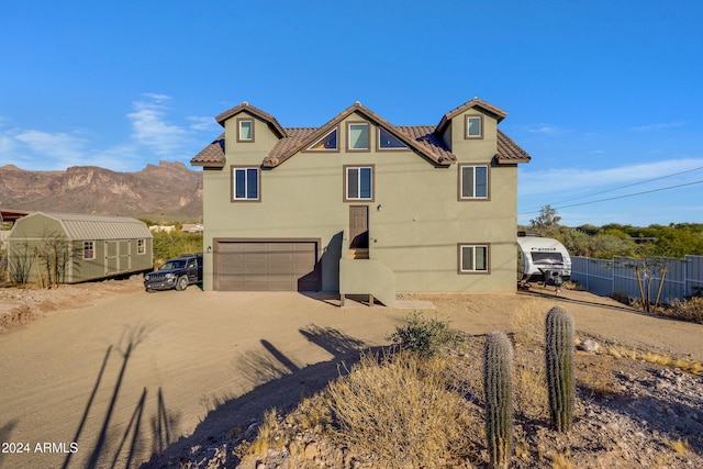 rear view of house featuring a mountain view, a storage unit, and a garage