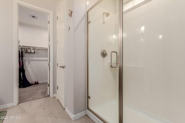 bathroom with an enclosed shower and wood-type flooring