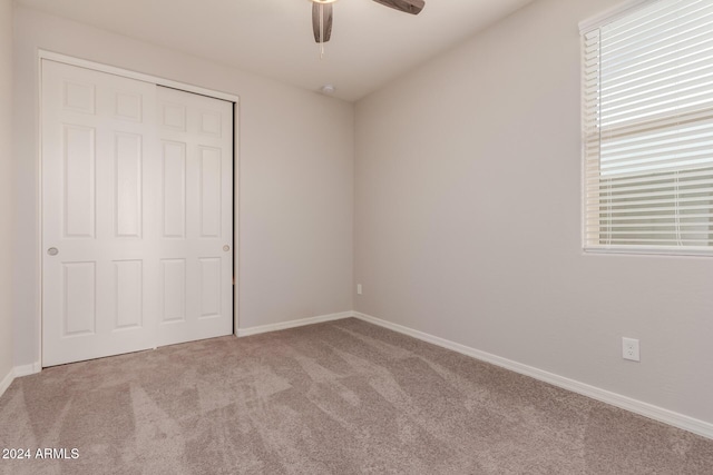 unfurnished bedroom featuring light colored carpet, a closet, and ceiling fan