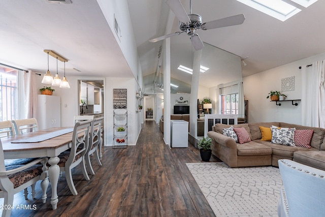 living room featuring vaulted ceiling with skylight, ceiling fan, and dark hardwood / wood-style floors