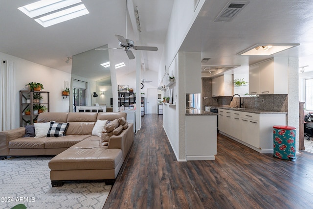 living room featuring ceiling fan, sink, dark wood-type flooring, and a skylight