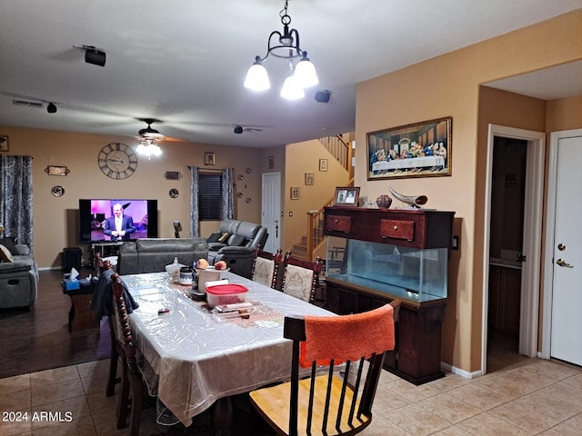 tiled dining room with ceiling fan with notable chandelier