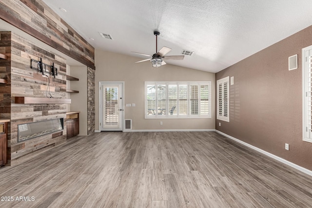 3028 W Parkside Ln, Phoenix, AZ 85027 - unfurnished living room with a glass covered fireplace, ceiling fan, light wood-type flooring, vaulted ceiling, and a textured ceiling