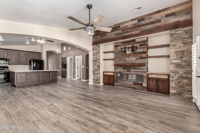3028 W Parkside Ln, Phoenix, AZ 85027 - unfurnished living room featuring ceiling fan, arched walkways, light wood finished floors, vaulted ceiling, and a fireplace