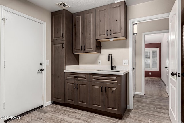 3028 W Parkside Ln, Phoenix, AZ 85027 - kitchen featuring a sink, light countertops, dark brown cabinetry, light wood-type flooring, and baseboards