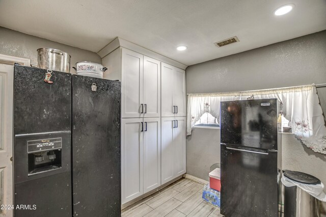 2124 W Maricopa St, Phoenix, AZ 85009 - kitchen featuring freestanding refrigerator, black fridge, white cabinetry, recessed lighting, and wood finish floors