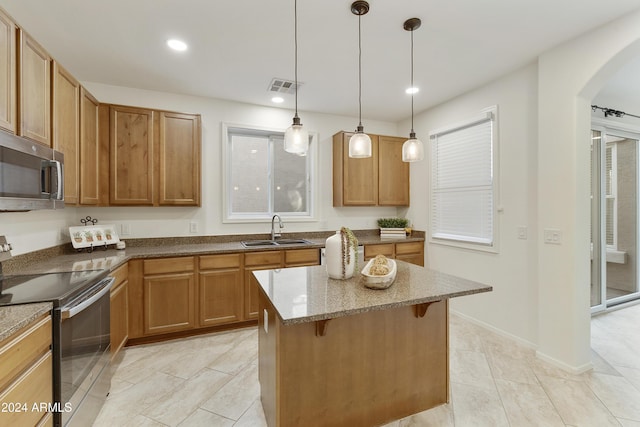 kitchen with a breakfast bar, sink, stainless steel appliances, and hanging light fixtures