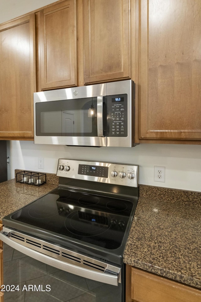 kitchen featuring dark stone counters, tile patterned floors, and stainless steel appliances