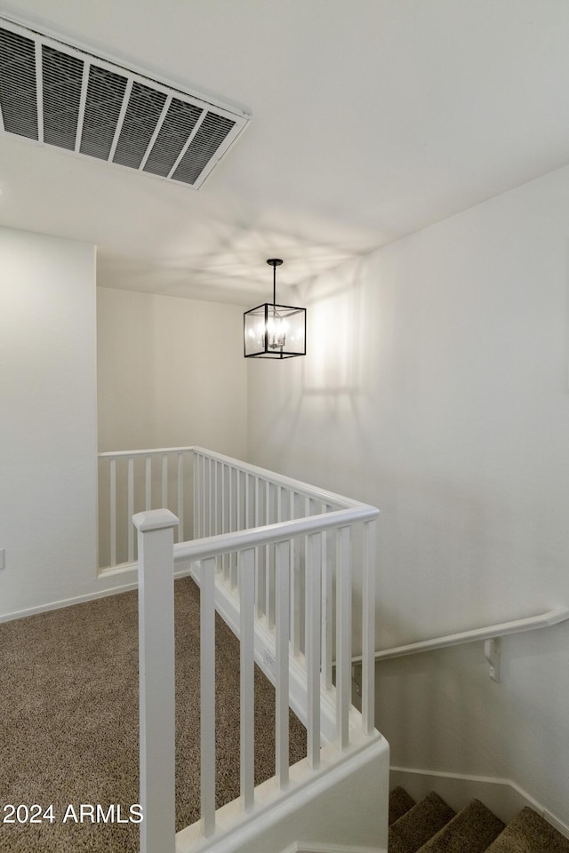 staircase featuring carpet flooring and a chandelier