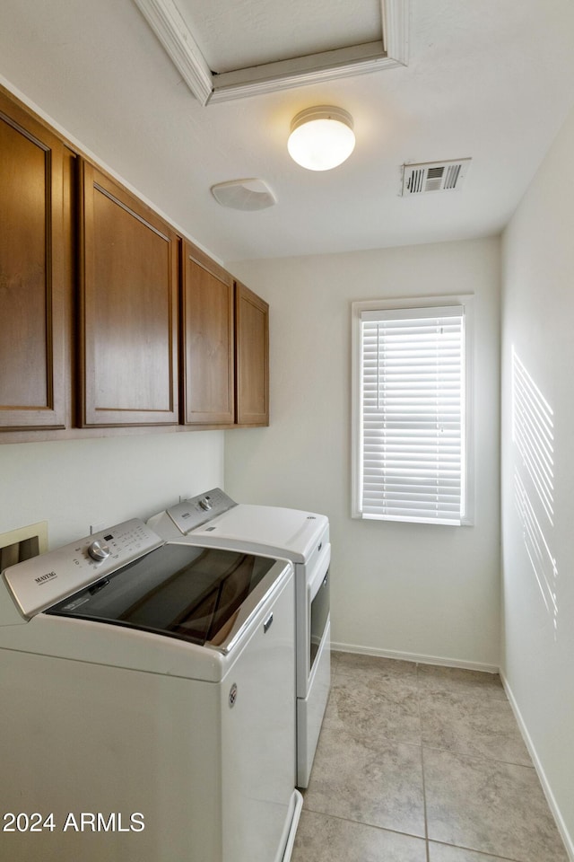 laundry room with cabinets, light tile patterned flooring, and washing machine and clothes dryer