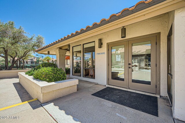 9707 E Mountain View Rd Unit 1408, Scottsdale, AZ 85258 - view of exterior entry featuring french doors, stucco siding, and a tiled roof