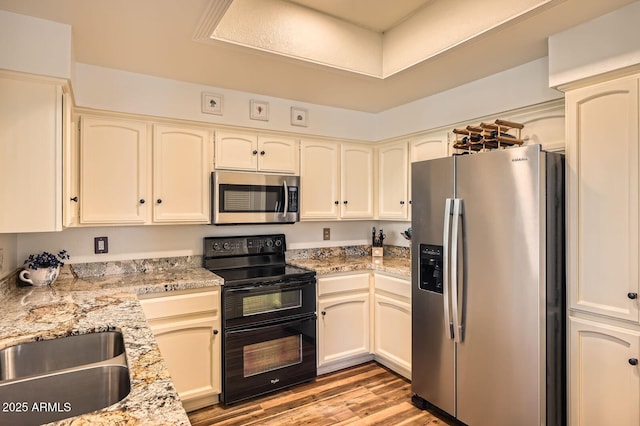 9707 E Mountain View Rd Unit 1408, Scottsdale, AZ 85258 - kitchen with appliances with stainless steel finishes, light wood finished floors, light stone counters, a sink, and cream cabinetry