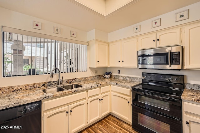 9707 E Mountain View Rd Unit 1408, Scottsdale, AZ 85258 - kitchen with black appliances, a sink, light wood-type flooring, cream cabinetry, and light stone counters