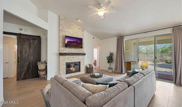 1213 W Beck Ln, Phoenix, AZ 85023 - living room with vaulted ceiling, a barn door, a ceiling fan, light wood finished floors, and arched walkways