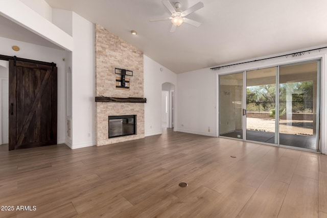 1213 W Beck Ln, Phoenix, AZ 85023 - unfurnished living room featuring ceiling fan, arched walkways, a barn door, a fireplace, and wood finished floors